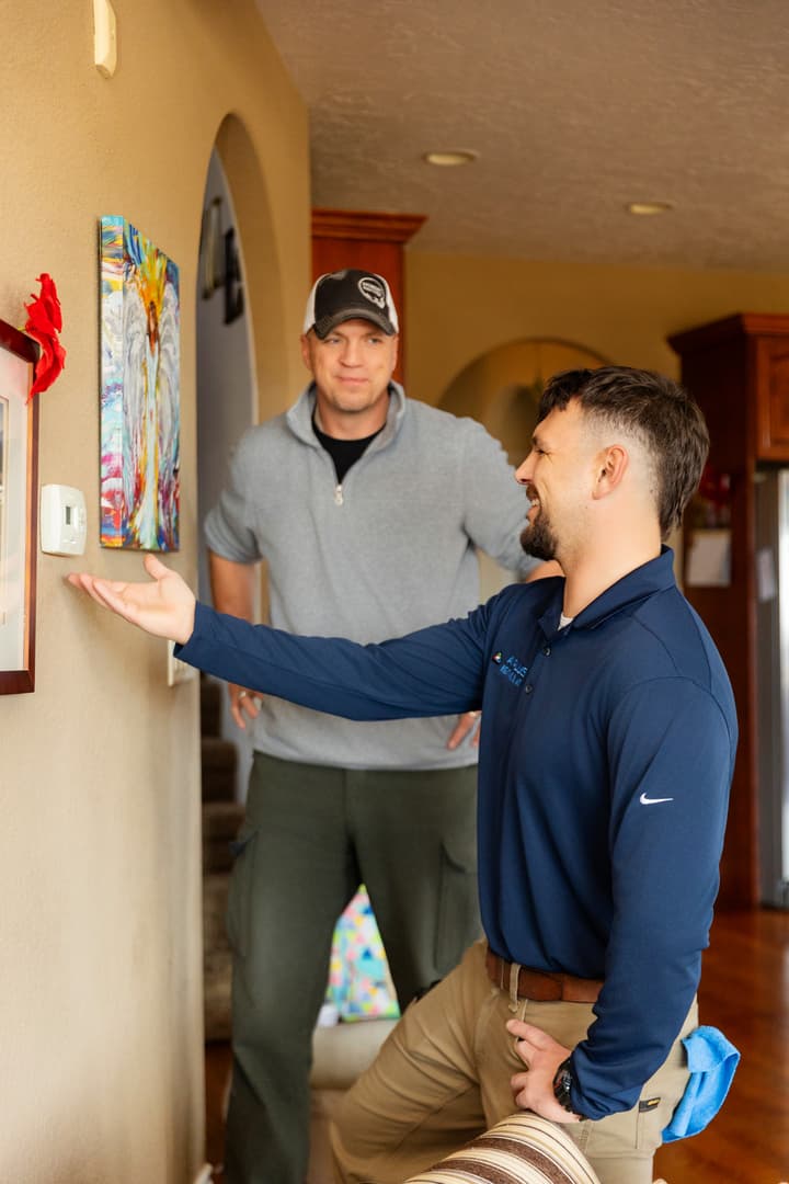 A Plus technician explaining thermostat settings to a homeowner